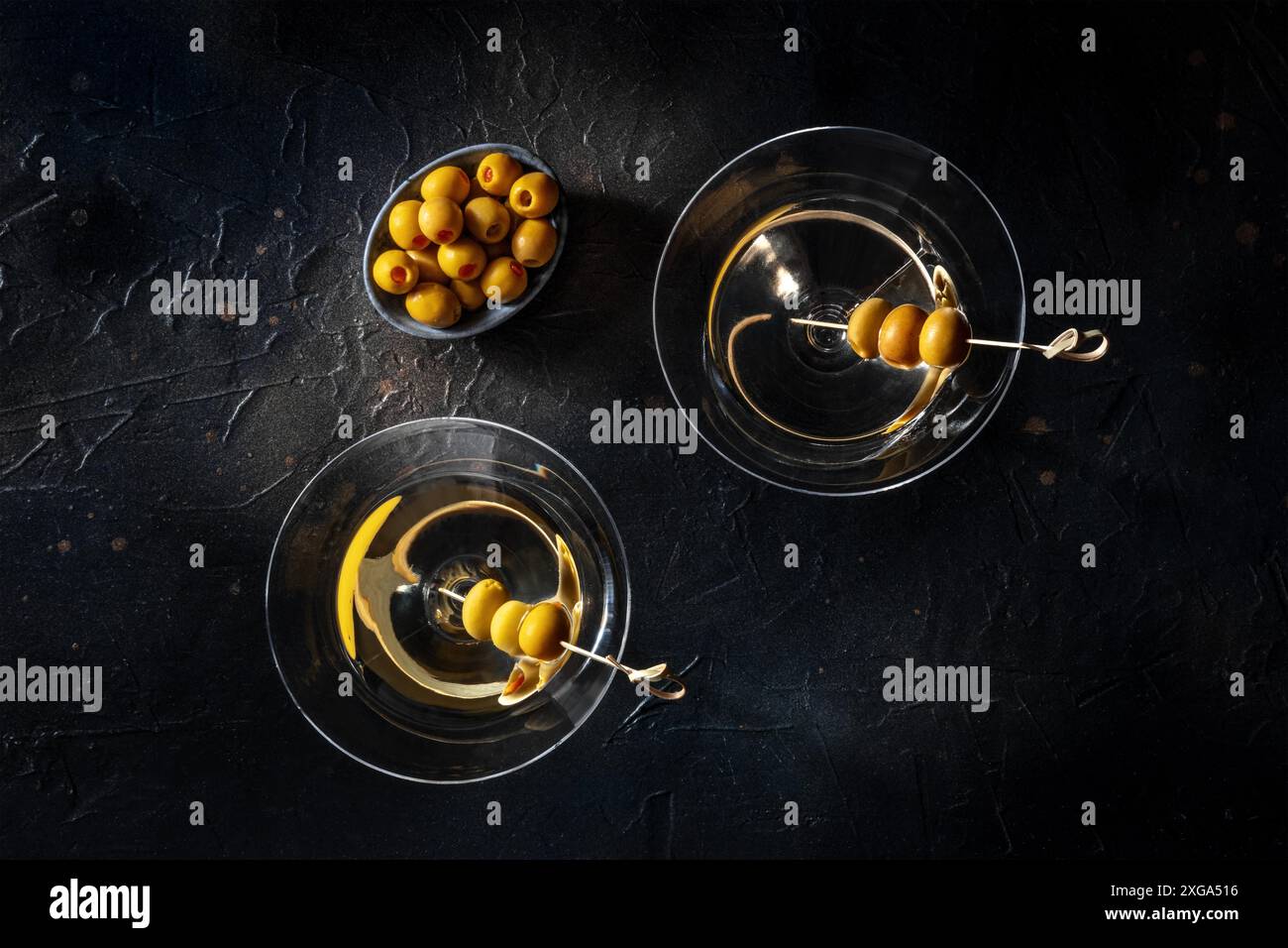 Martini, due bicchieri con olive speziate, su sfondo nero. Cocktail alcolici, scatto a forma di piatto Foto Stock
