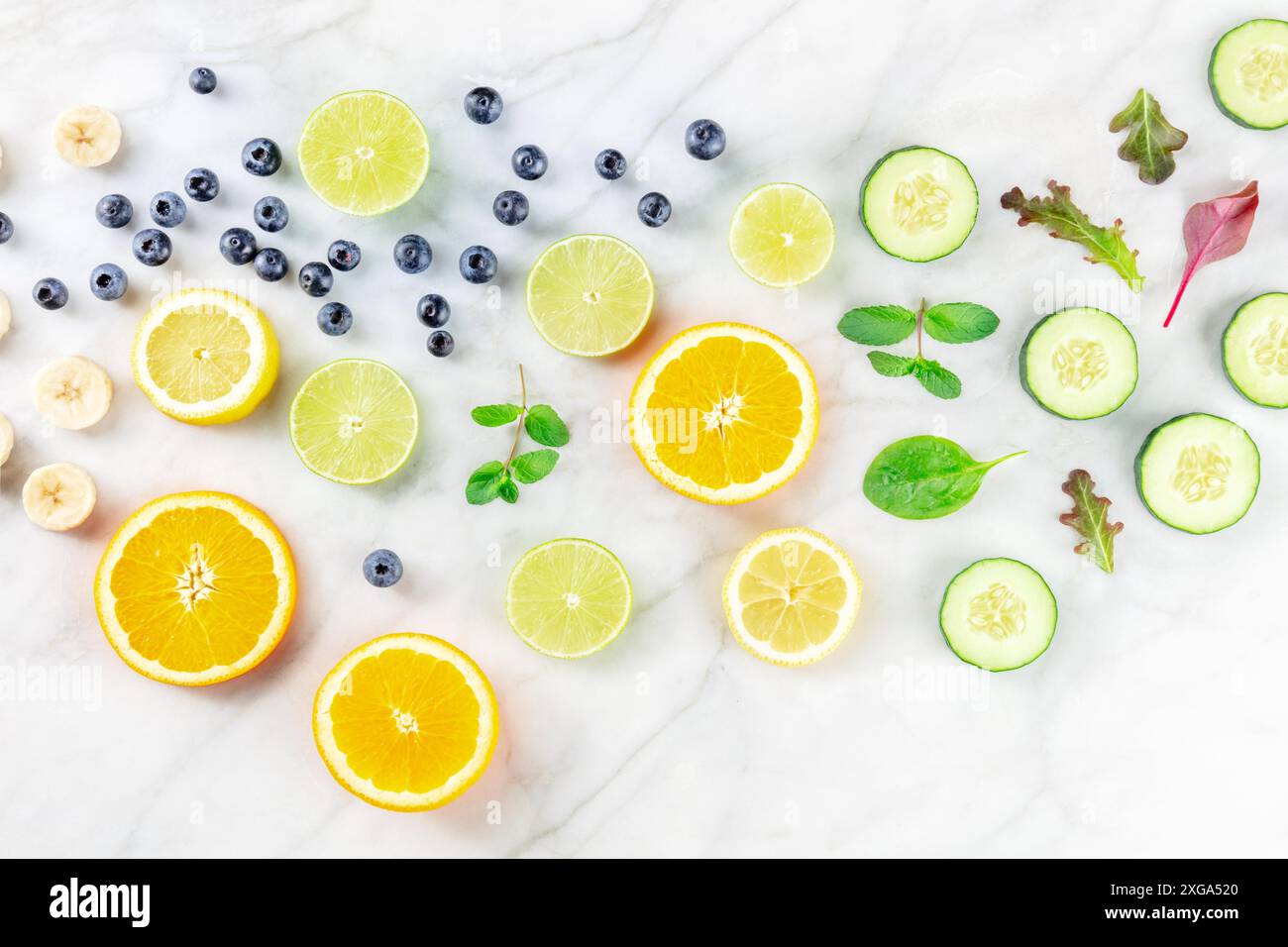 Cibo estivo fresco. Fette di agrumi e verdure, sopra un tavolo da cucina in marmo bianco. Dieta sana a base di piante Foto Stock