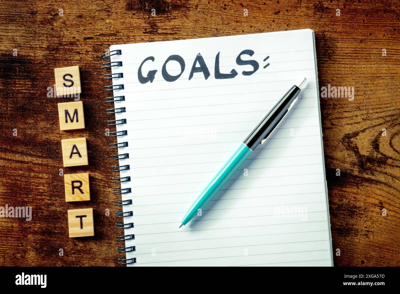 Concetto Smart Goals. Un blocco note con la parola manoscritta, per scrivere un piano o una lista, sopra la testa piatta stendere sparato su una scrivania di legno Foto Stock