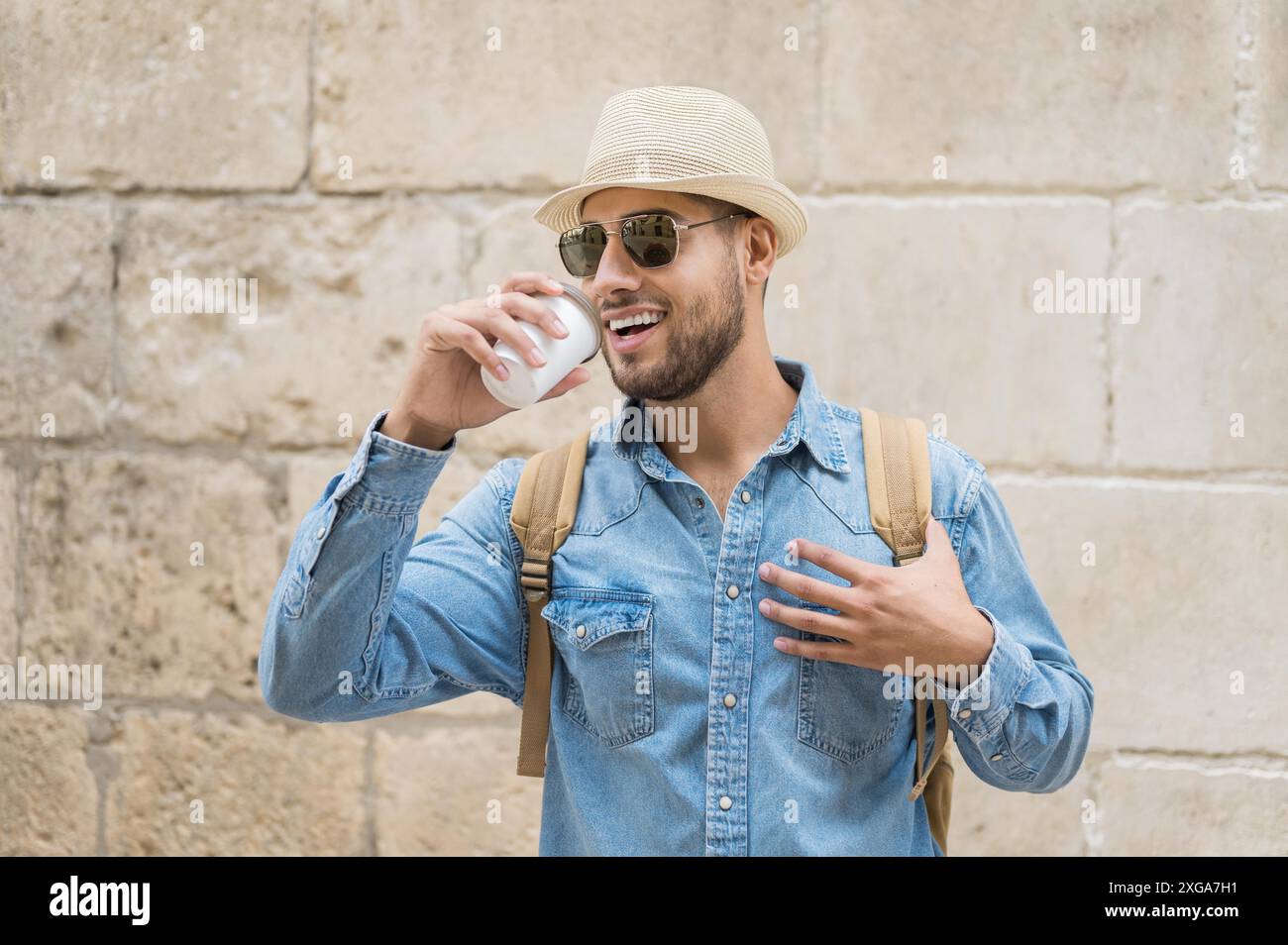 Felice giovane turista con caffè da andare e zaino a piedi sulla strada. Foto di alta qualità Foto Stock