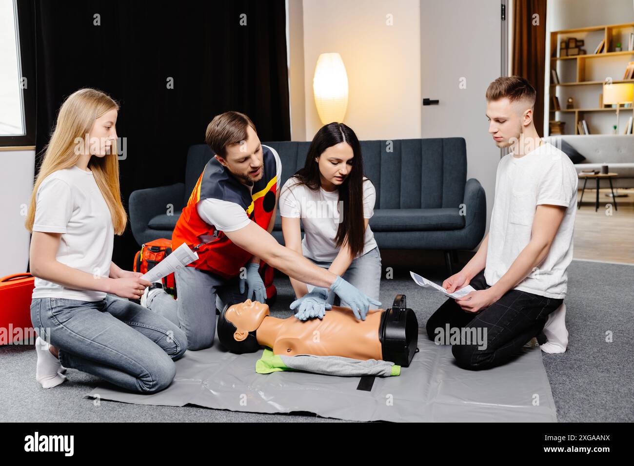 Gruppo di persone che imparano a fare le compressioni di cuore di primo soccorso con i dummies durante l'addestramento all'interno. Foto Stock