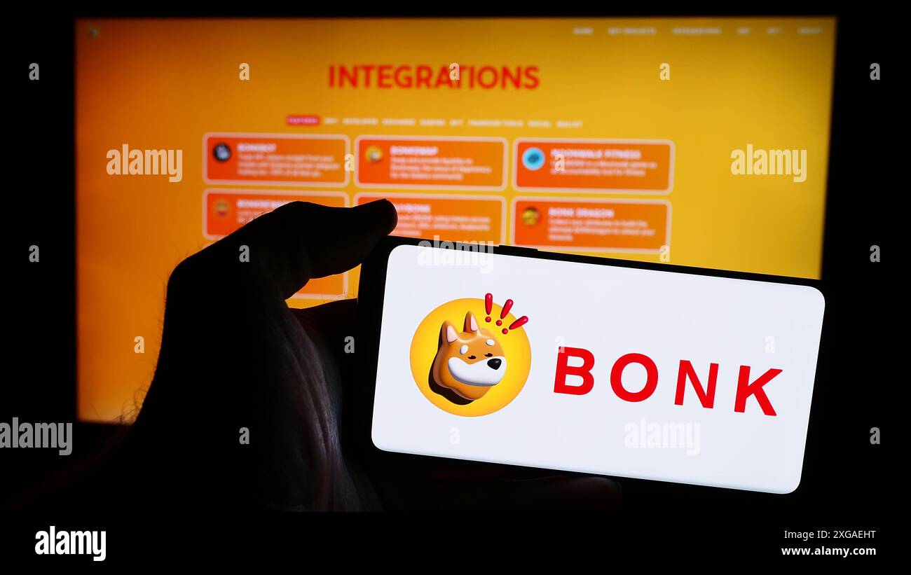 Persona che detiene un telefono cellulare con il logo della compagnia di monete per cani Bonk Inu di fronte alla pagina web aziendale. Mettere a fuoco il display del telefono. Foto Stock