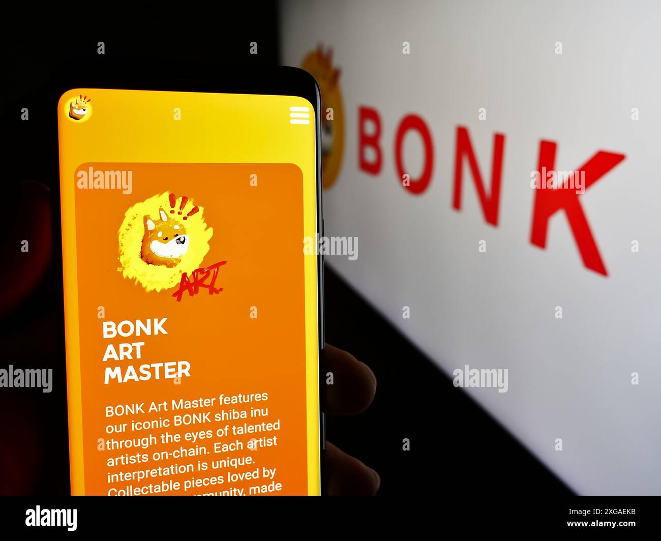 Persona che tiene un cellulare con la pagina web della compagnia di monete per cani Bonk Inu davanti al logo aziendale. Messa a fuoco al centro del display del telefono. Foto Stock