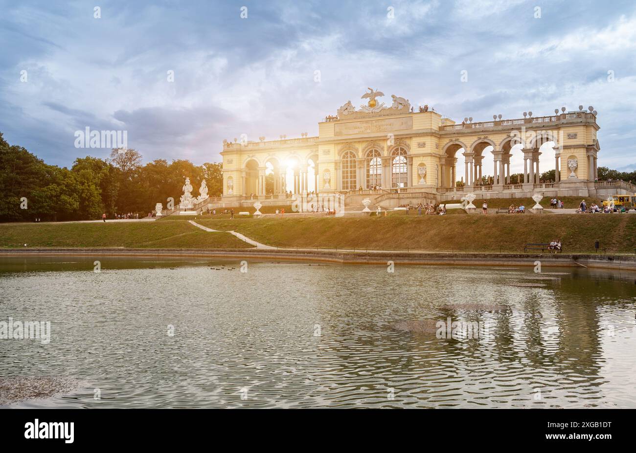 Vienna, Austria, 20 agosto 2022. La Gloriette si trova in cima alla collina nei giardini del Palazzo Schönbrunn. Persone lungo il percorso del tour al tramonto. Foto Stock