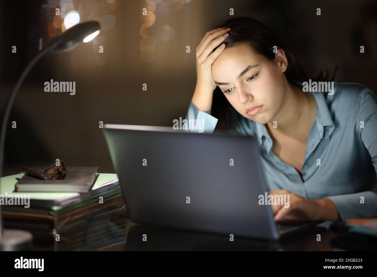 Lavoratore sopraffatto che lavora online con un notebook di notte Foto Stock