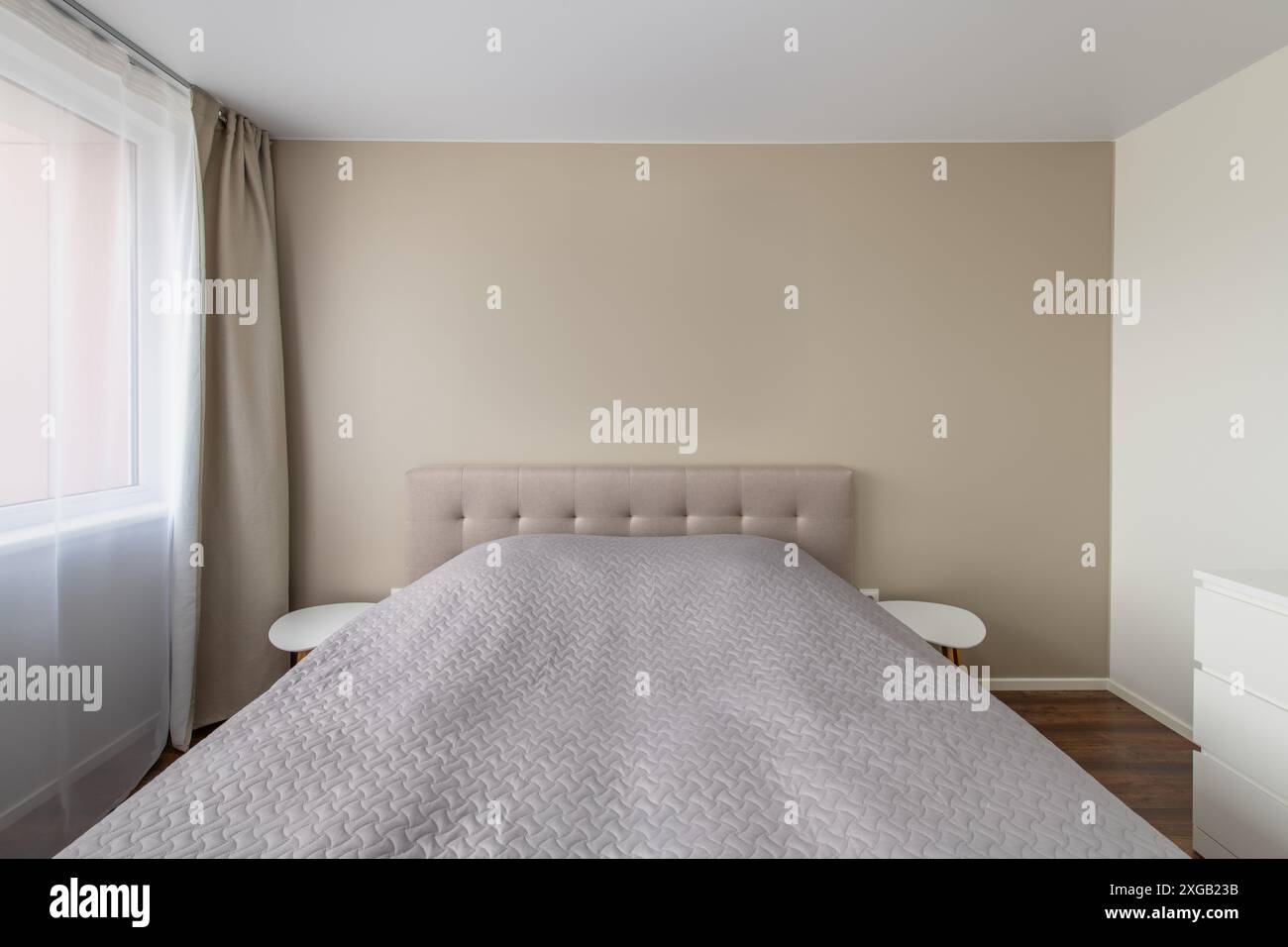 Minimalismo bambini, interno soggiorno per adulti. Letto e tavolino da caffè. Coperta grigia sul letto. Finestre e tende. Luce LED Foto Stock