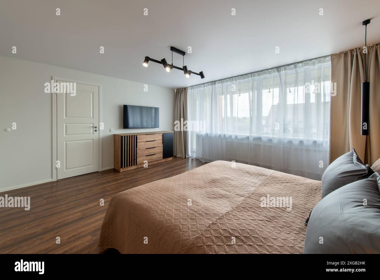 Interni lussuosi della camera da letto principale, casa moderna, splendidi interni, ampia camera da letto. TV sulla parete. Porta di uscita bianca Foto Stock