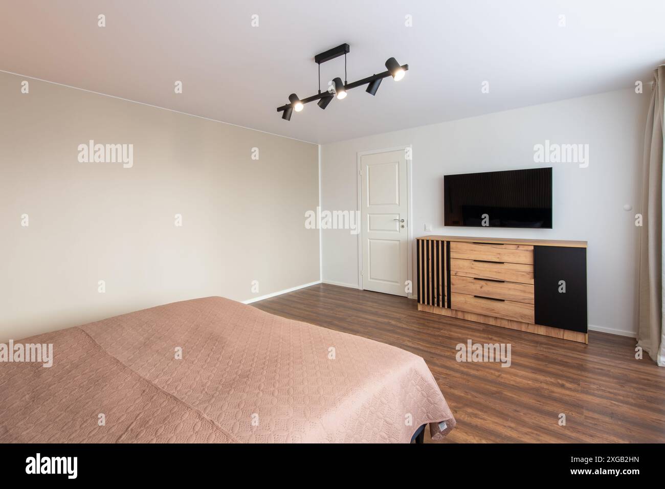 Interni lussuosi della camera da letto principale, casa moderna, splendidi interni, ampia camera da letto. TV sulla parete. Porta di uscita bianca Foto Stock