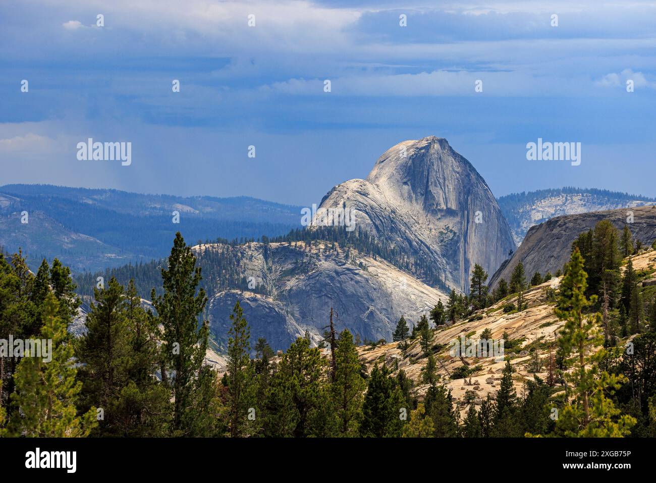 Il sole attraversa le nuvole per illuminare Half Dome, un'iconica formazione rocciosa di granito nella Yosemite Valley, Yosemite National Park, California, USA. Foto Stock