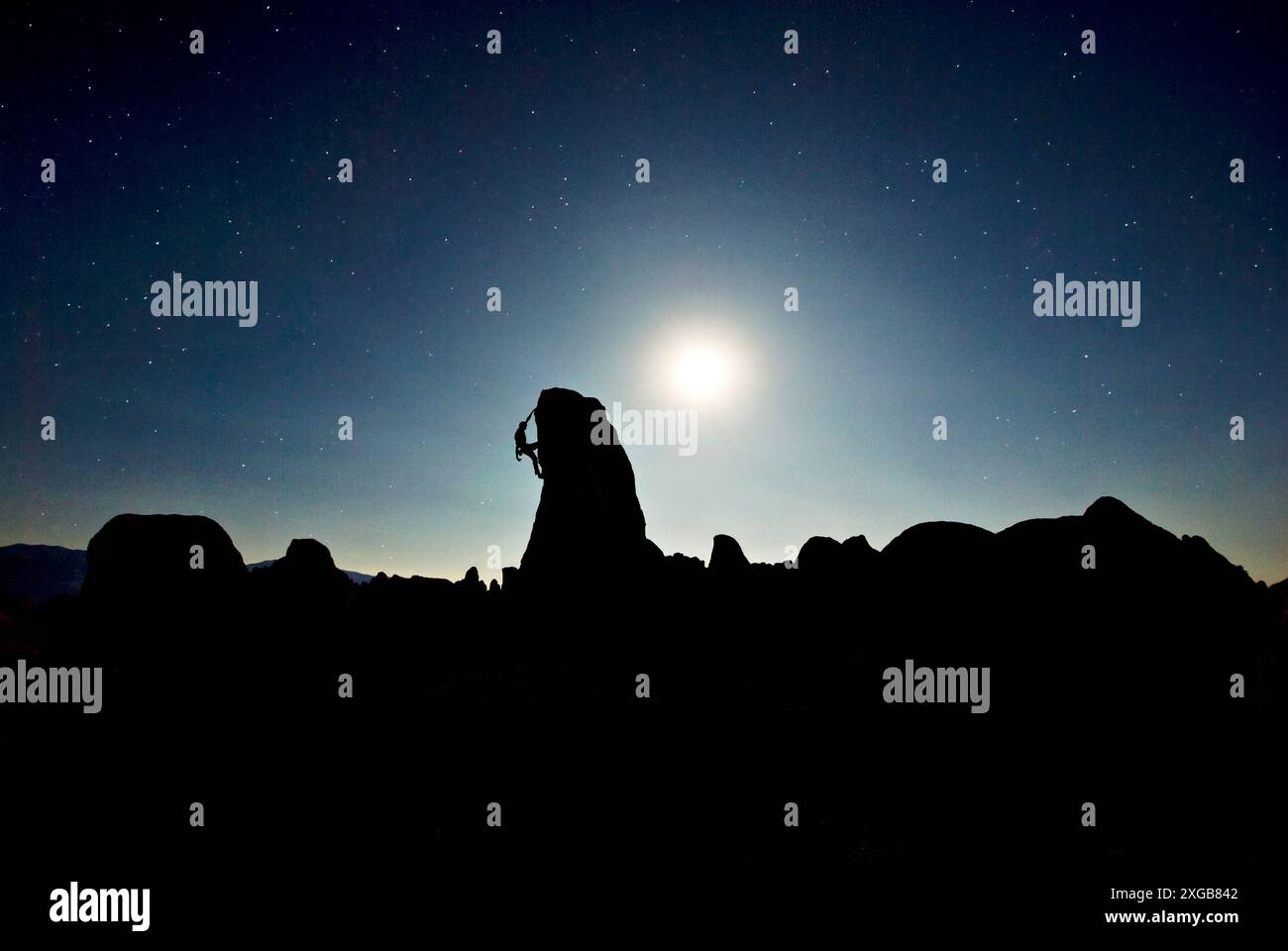 Un alpinista risolve un problema sotto la luna piena nelle Alabama Hills, Lone Pine, CALIFORNIA. Foto Stock