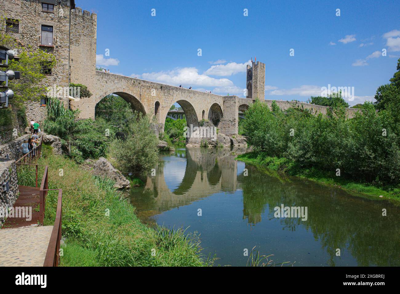 Girona, Spagna - 7 luglio 2024: Riflessioni del ponte medievale Pont Vell sul fiume Fluvia a Besalu, Catalogna Foto Stock
