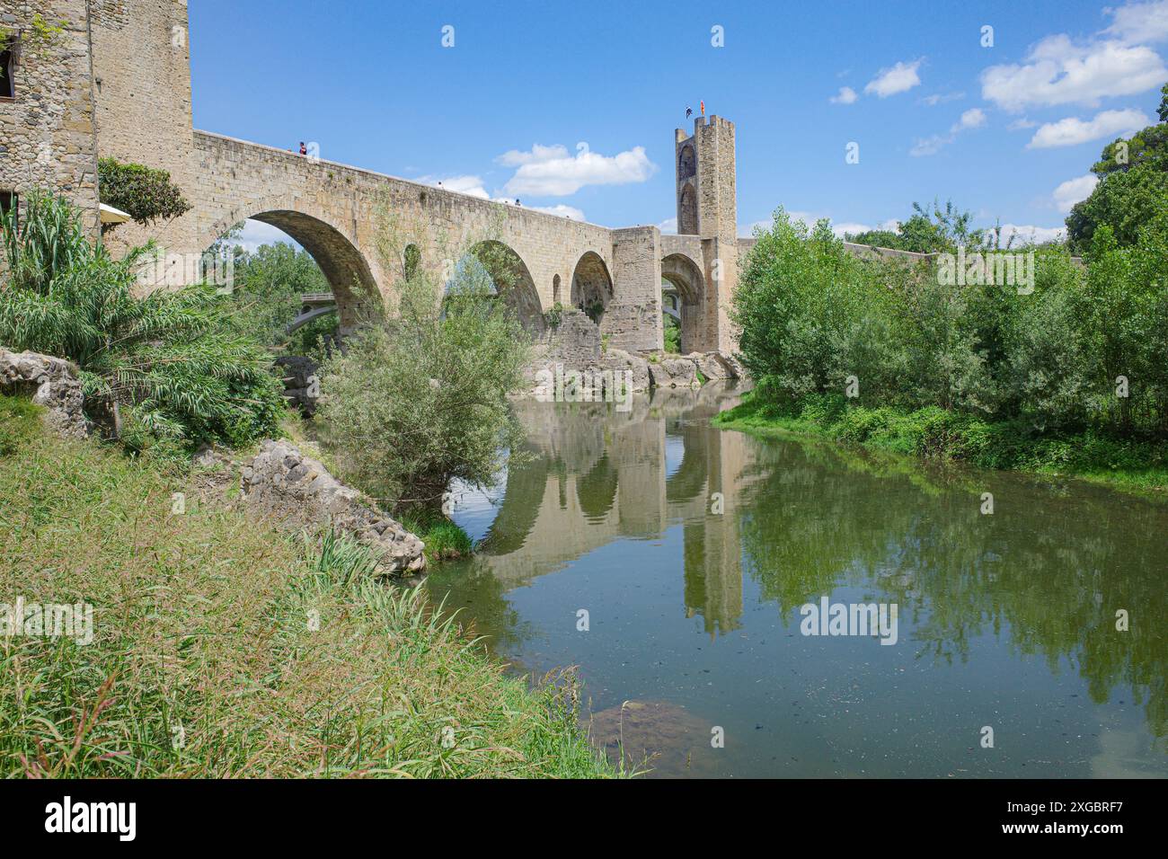 Girona, Spagna - 7 luglio 2024: Riflessioni del ponte medievale Pont Vell sul fiume Fluvia a Besalu, Catalogna Foto Stock
