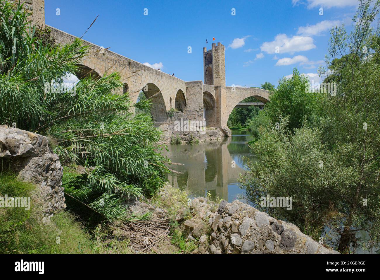 Girona, Spagna - 7 luglio 2024: Riflessioni del ponte medievale Pont Vell sul fiume Fluvia a Besalu, Catalogna Foto Stock