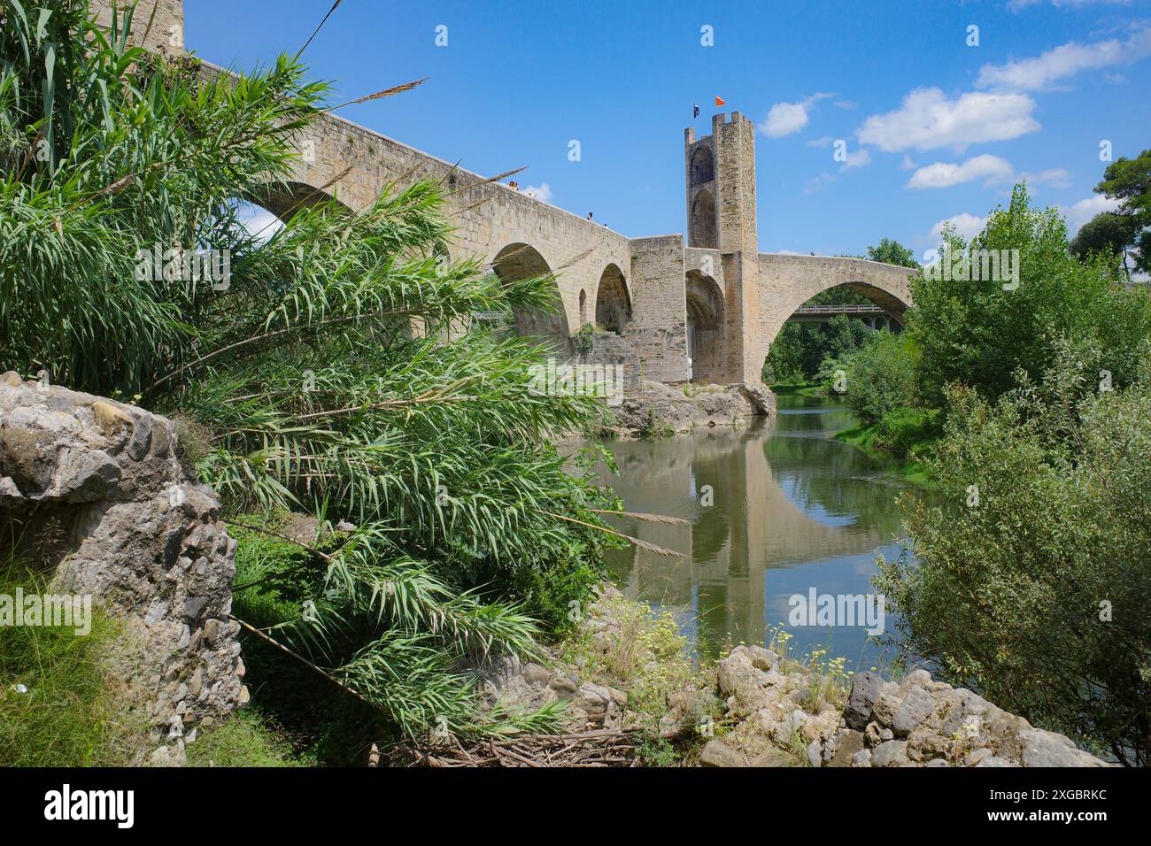 Girona, Spagna - 7 luglio 2024: Riflessioni del ponte medievale Pont Vell sul fiume Fluvia a Besalu, Catalogna Foto Stock