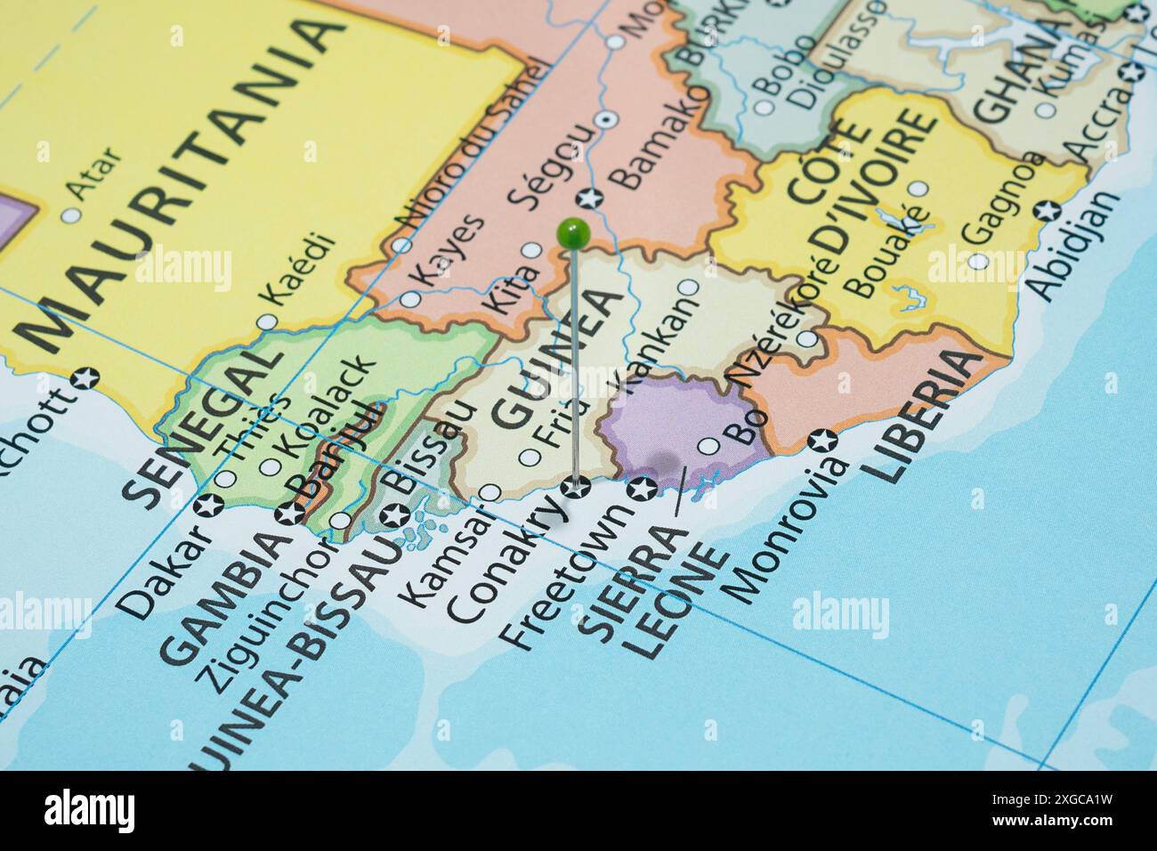 Avvicinati a una città di Conarkry con un ago di spillo verde sulla mappa politica del paese della Guinea Foto Stock