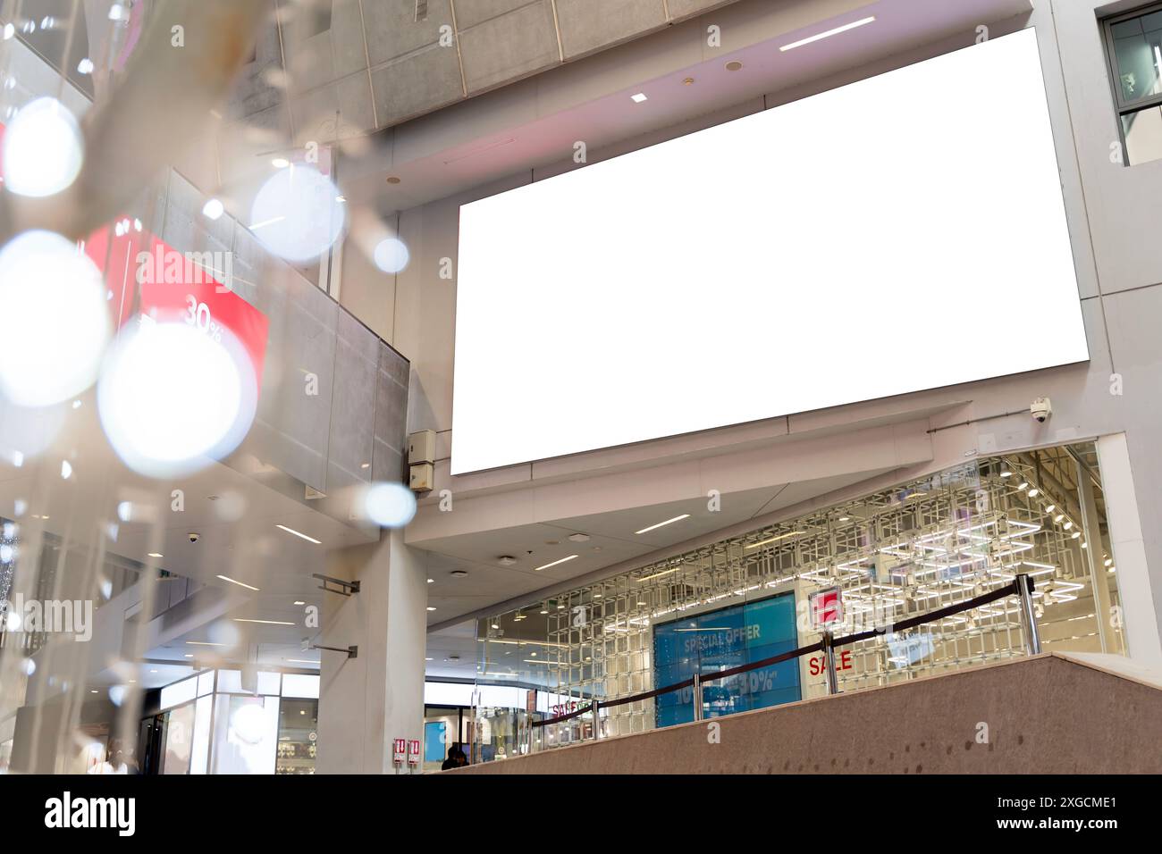 Un grande cartellone bianco pende dal soffitto di un centro commerciale. Il cartellone è vuoto. Il cartellone si trova in un'area ad alto traffico, dove si trova Foto Stock