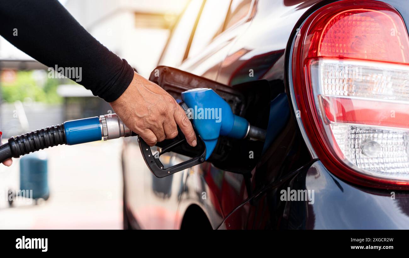 L'autista manuale riempie e pompa benzina l'auto con carburante presso la stazione di rifornimento. Rifornimento di carburante presso la stazione di rifornimento. Pompa carburante alla stazione. Refu Foto Stock