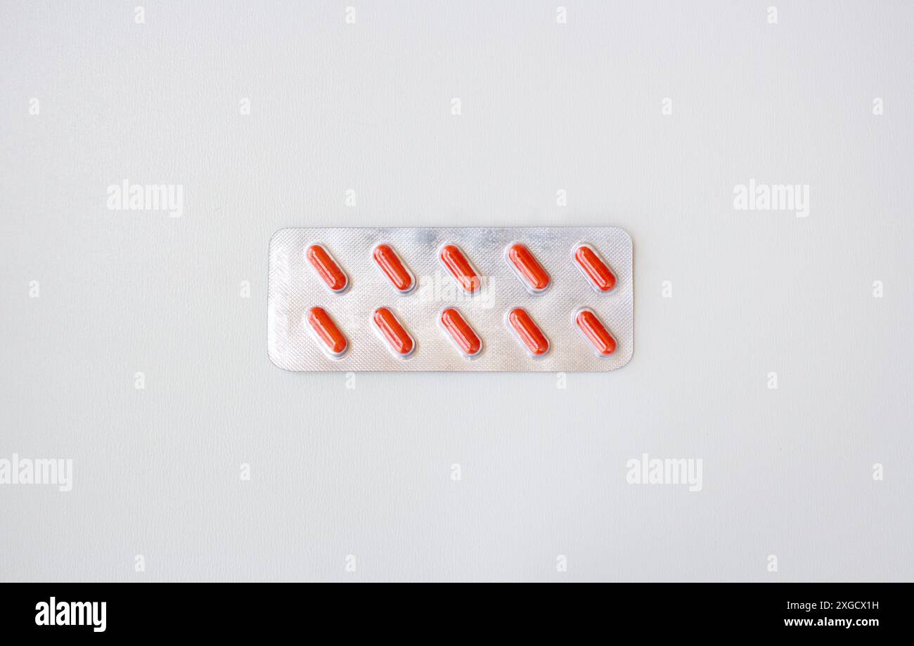 Capsule mediche rosse confezionate in blister isolato su sfondo bianco. Striscione orizzontale con spazio per la copia. Farmacia, trattamento, concetto di problema di salute Foto Stock