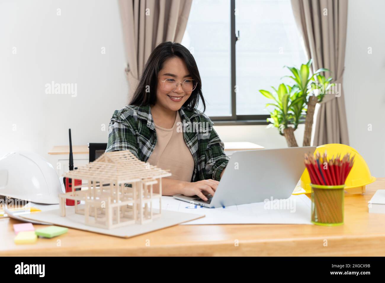 Una donna matura guarda un notebook nel suo ufficio, sicura della sua esperienza e del suo stile creativo. Senior design Professional che utilizza un notebook e Foto Stock