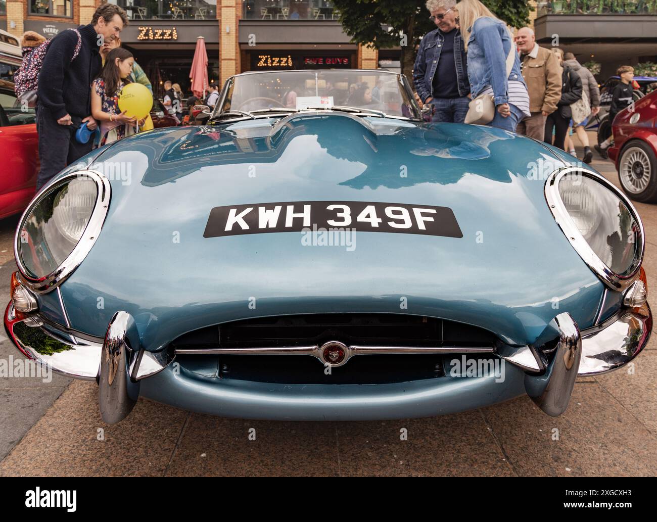 Gli appassionati di auto si riuniscono intorno a una Jaguar e Typre degli anni '1960, una vera auto sportiva classica britannica. L'iconico cofano e TYPE Jag. Tradizione automobilistica britannica. Foto Stock