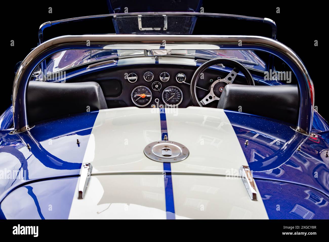 Vista posteriore di un veicolo in stile AC Cobra. Una prospettiva elegante attraverso la cabina di pilotaggio, che cattura le sue curve classiche, il fascino vintage e la tradizione delle corse. Foto Stock