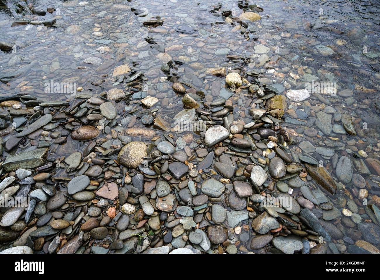 Primo piano di ciottoli di fiume in acque poco profonde, sponda del fiume. Zen e rilassante immagine di sfondo Foto Stock