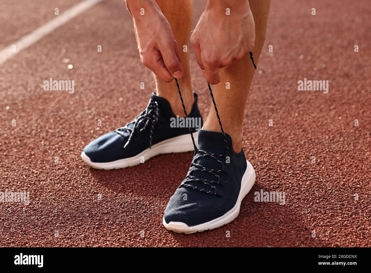 Uomo che lega scarpe di sneaker nera allo stadio, primo piano Foto Stock