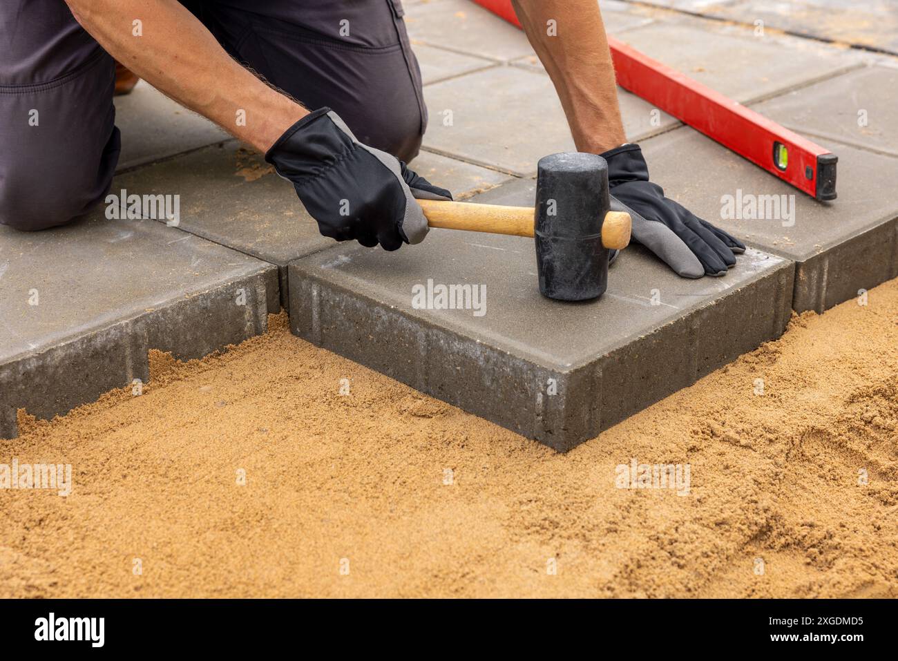 operatore che installa lastre di pavimentazione in calcestruzzo su fondamenta sabbiose Foto Stock