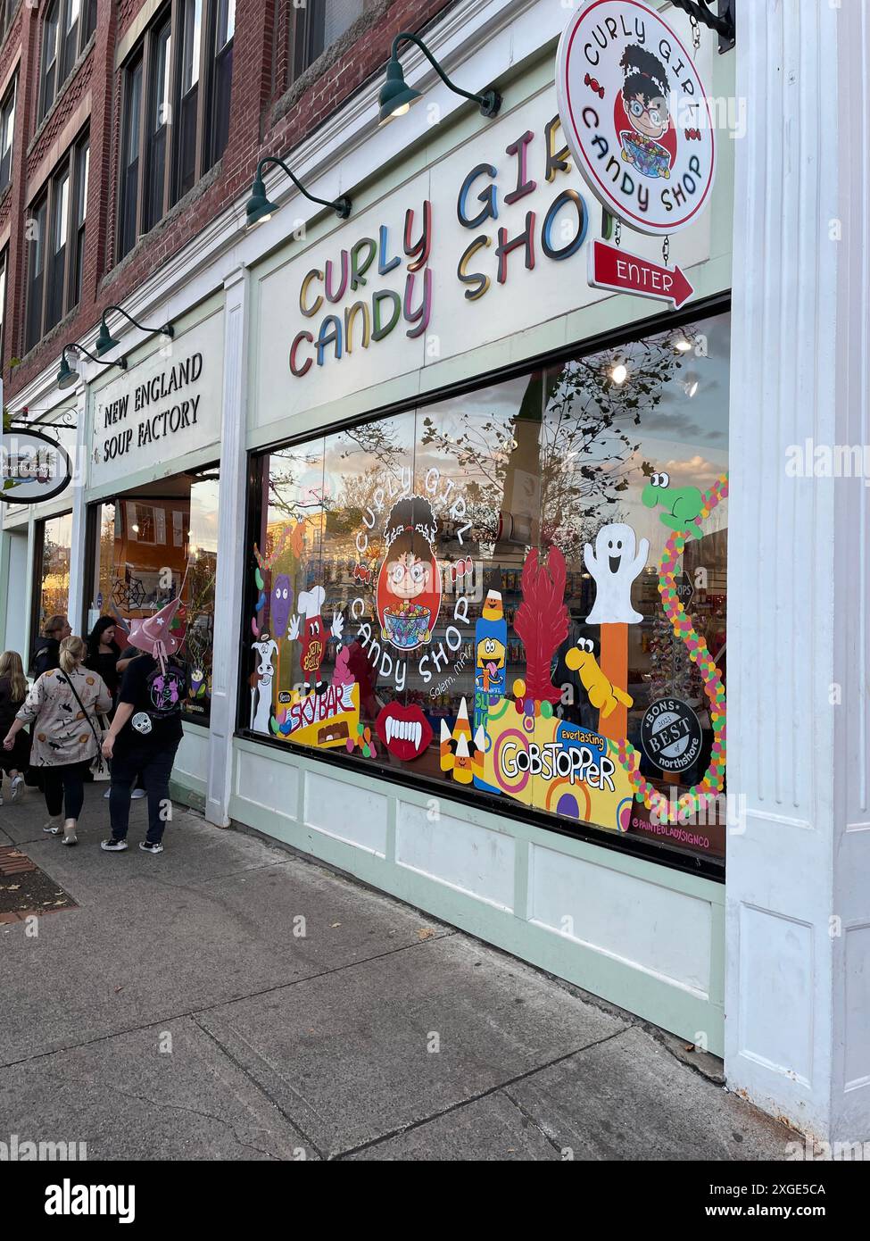 Le persone si riuniscono all'ingresso di un negozio di caramelle dove le vetrine del negozio sono dipinte e decorate per la festa di Halloween a Salem, Massachusetts Foto Stock