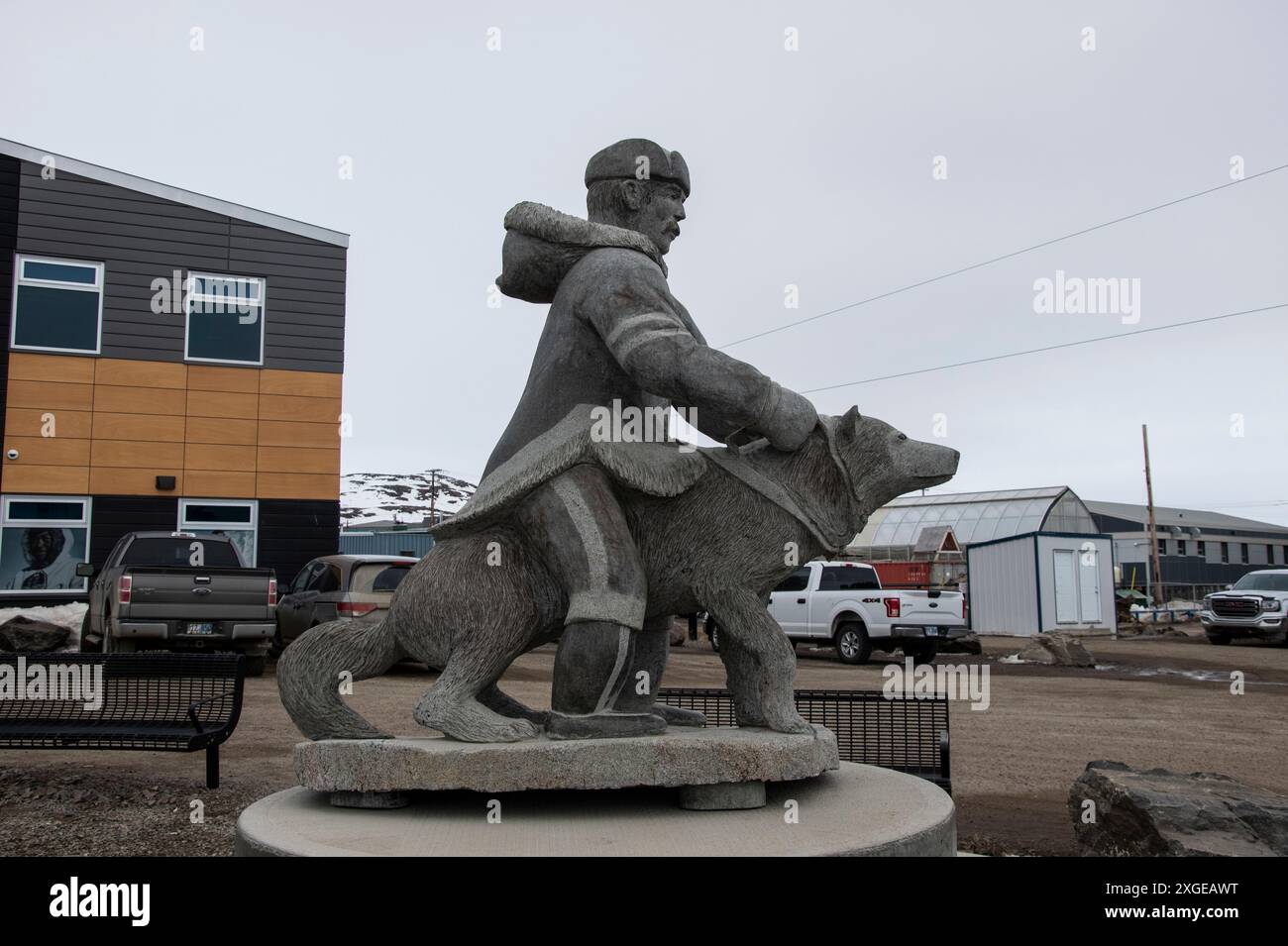 Scultura in pietra di un uomo e un cane Inuit nell'edificio RCMP sulla Federal Road a Iqaluit, Nunavut, Canada Foto Stock