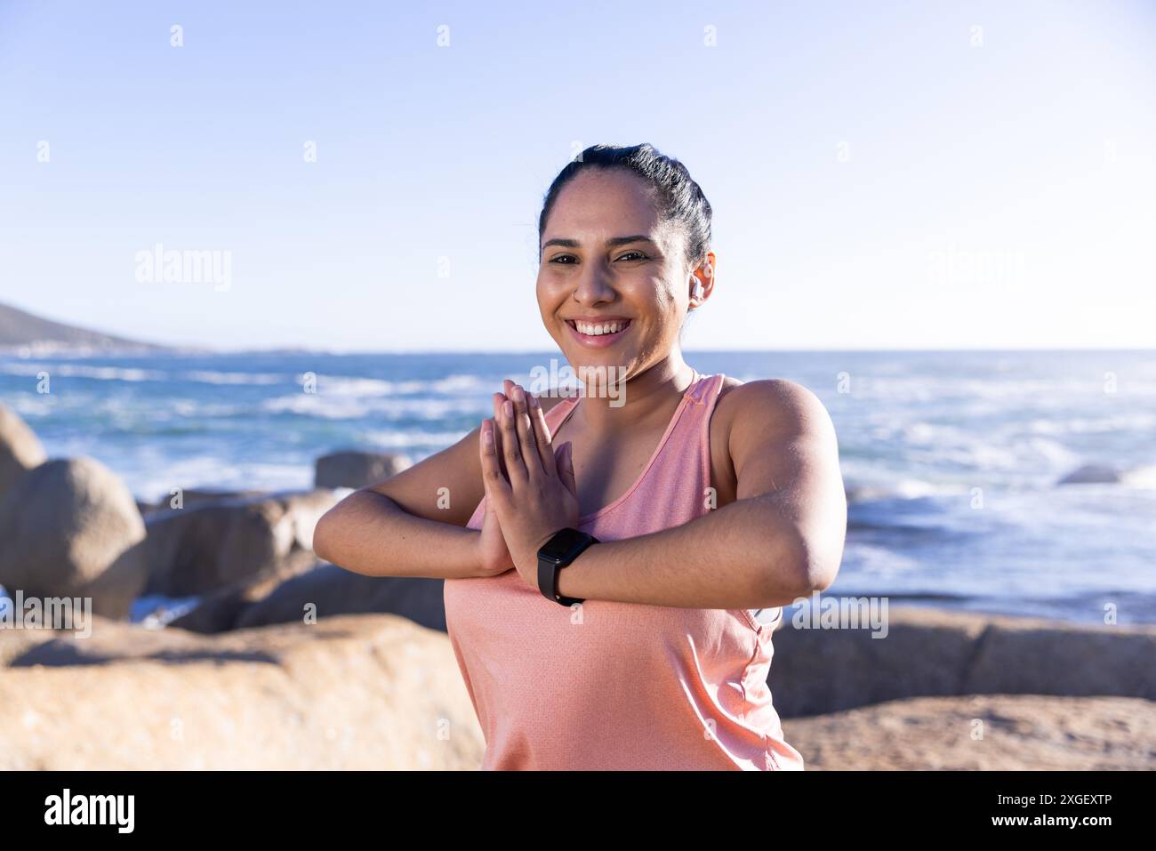 Praticare yoga, donna sorridente e posa in posizione di preghiera vicino all'oceano Foto Stock