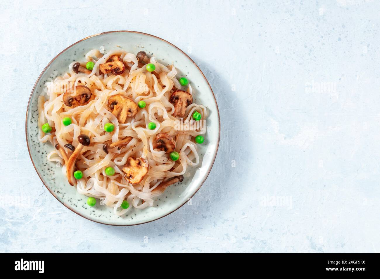 Pasta konjac con funghi e piselli verdi, sparata dall'alto con un posto per il testo Foto Stock