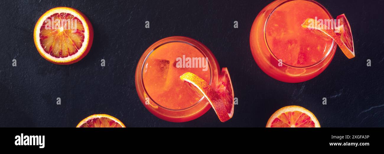 Panorama dei cocktail arancioni con arance di sangue, top shot su nero Foto Stock