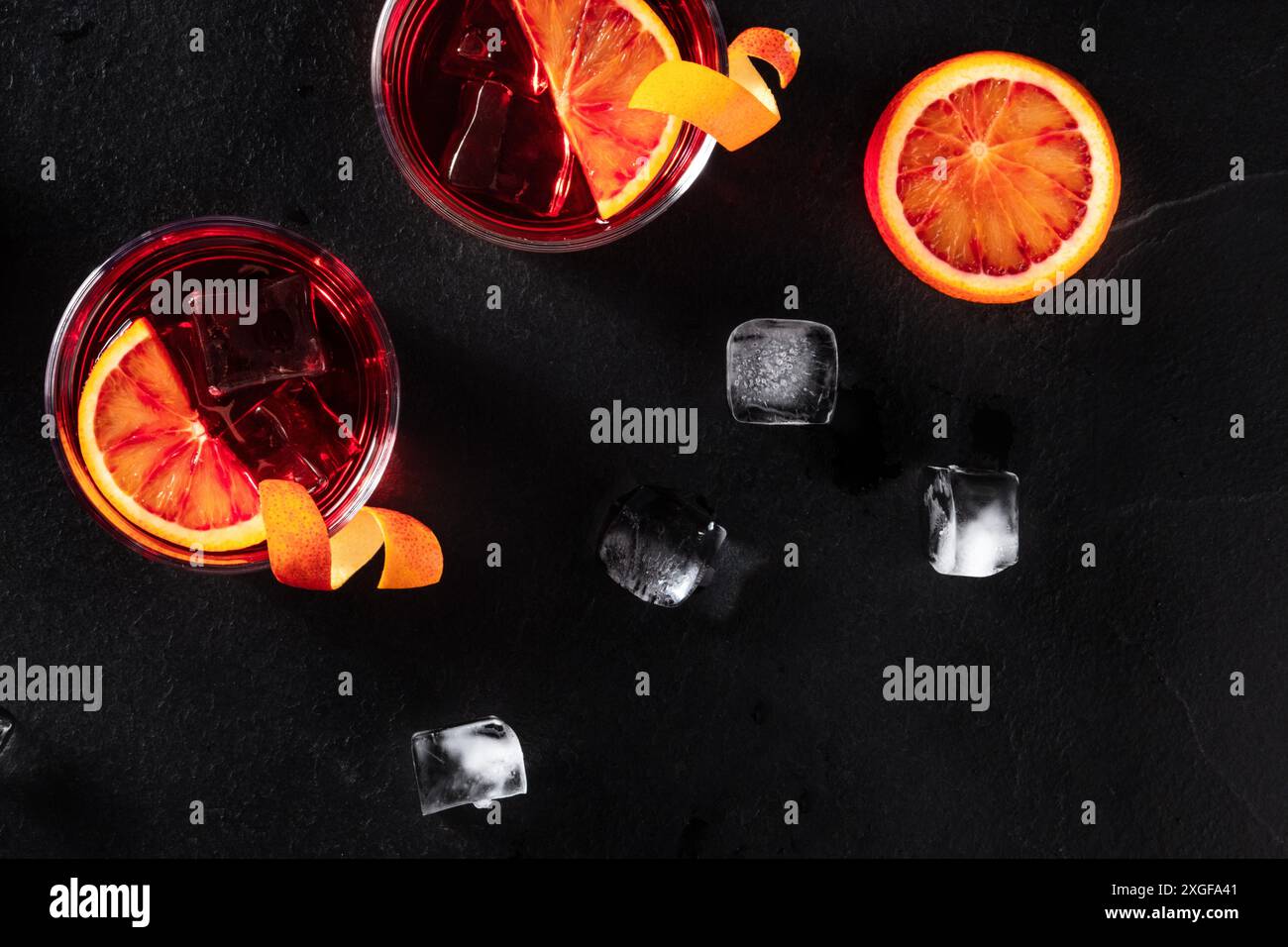 Cocktail arancioni con cubetti di ghiaccio, top shot su sfondo di ardesia nera Foto Stock