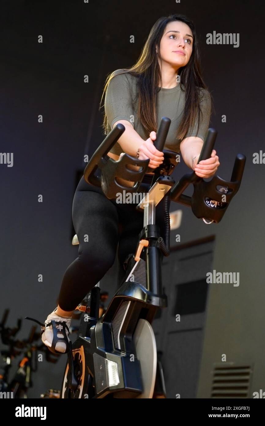 Donna in palestra che gira su una bicicletta fitness. Foto di alta qualità Foto Stock