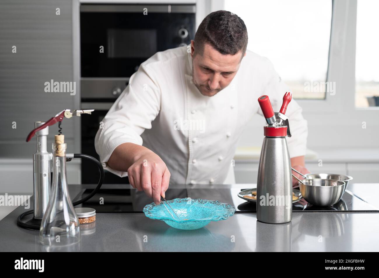 Raffinato ristorante chef preparare piatti deliziosi con sofisticati utensili in cucina commerciale. Foto di alta qualità Foto Stock