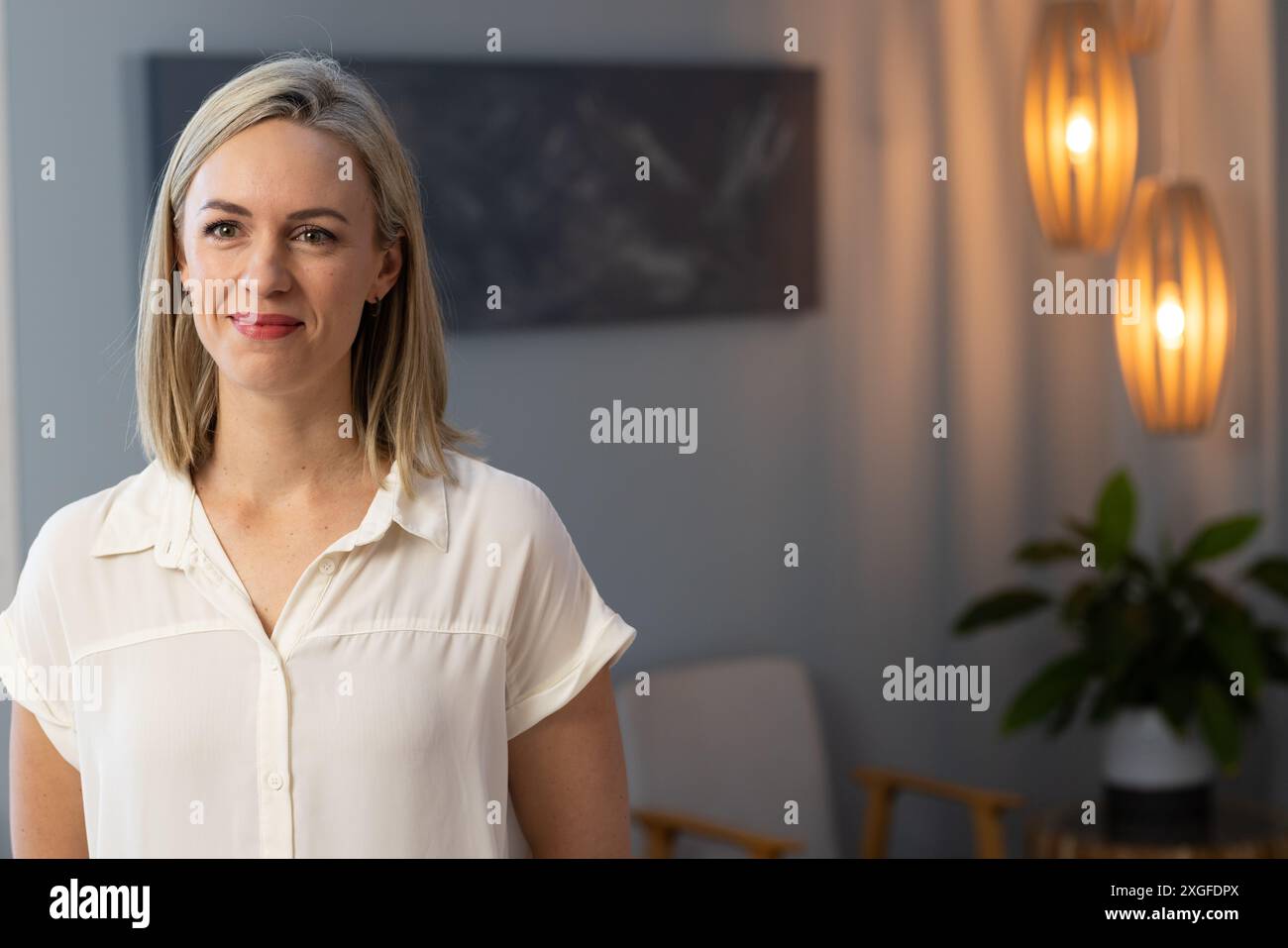 Donna sorridente in camicia bianca in piedi nel moderno ufficio della clinica medica, copia spazio Foto Stock