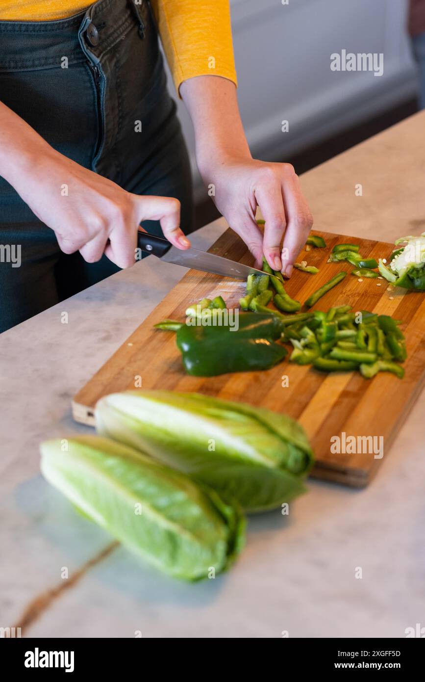 Tritare peperoni verdi sul tagliere, preparare verdure fresche Foto Stock