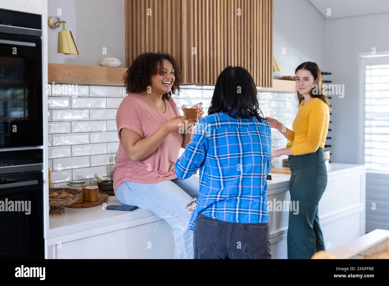 indefinito in cucina, chiacchierare e bere caffè, divertirsi insieme Foto Stock