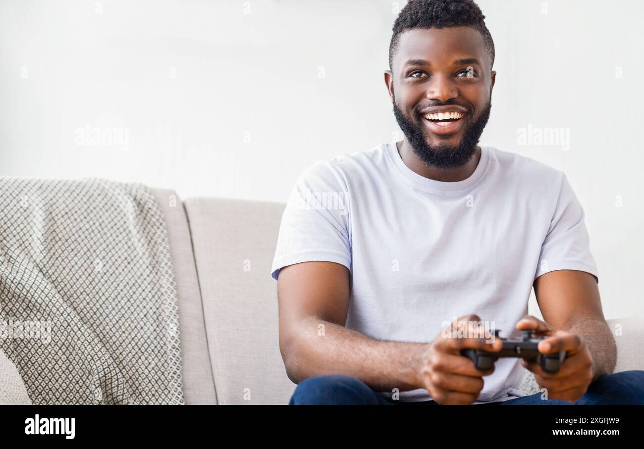 Uomo sorridente che gioca ai videogiochi sul divano Foto Stock