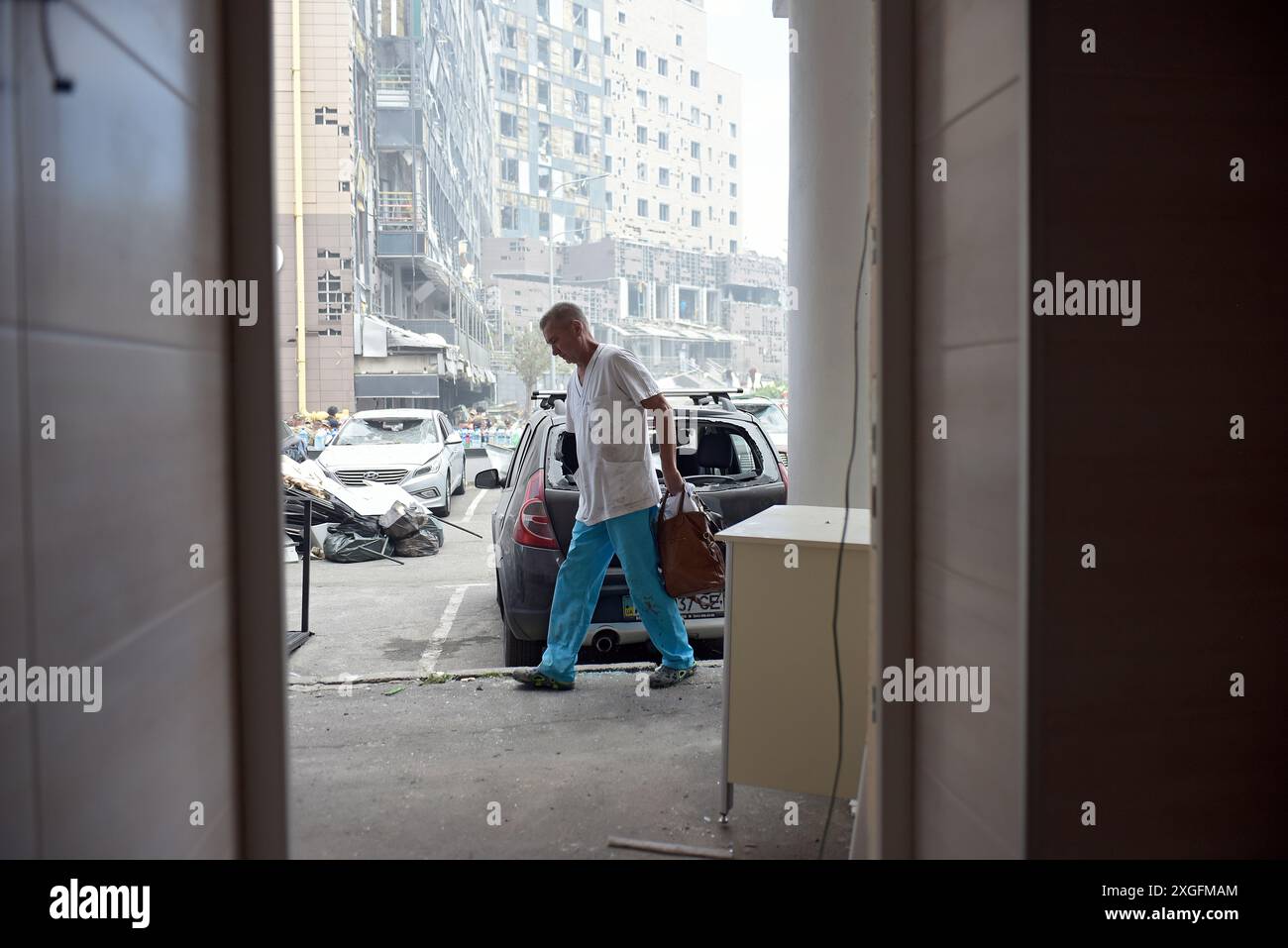 KIEV, UCRAINA - 8 LUGLIO 2024 - Un medico passa davanti a un'auto presso l'ospedale pediatrico specializzato nazionale Ohmatdyt attaccato dal missile crocieristico strategico russo KH-101, Kiev, capitale dell'Ucraina. Due adulti, tra cui un medico, sono stati uccisi e almeno 10 persone sono rimaste ferite all'ospedale Ohmatdyt. Foto Stock