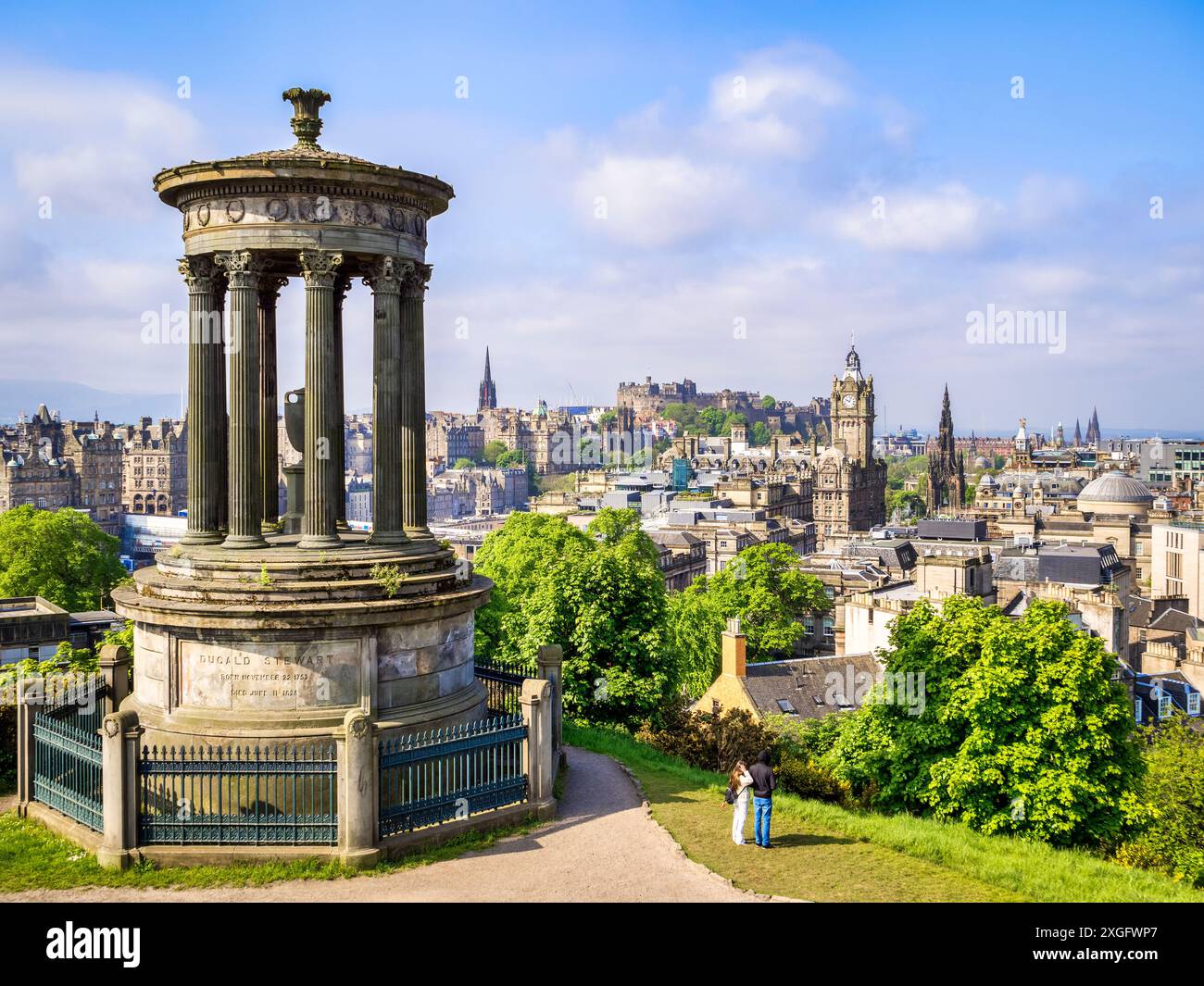 17 maggio 2024: Edimburgo, Scozia - il Dugald Stewart Memorial su Calton Hill, con vista su Edimburgo fino al castello. Giovane coppia che guarda la vista. Foto Stock