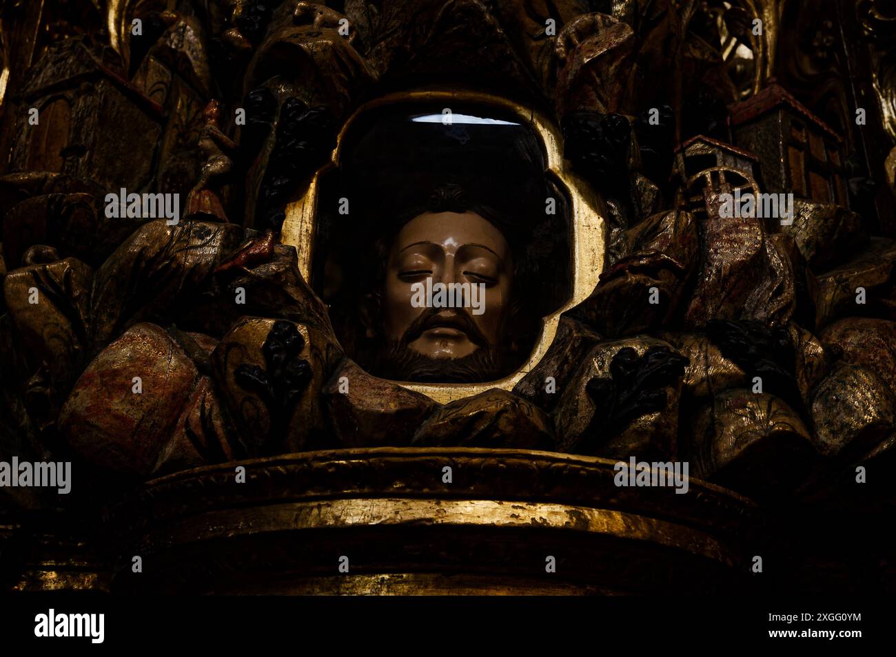 Una rappresentazione solenne del volto di un santo incapsulato in vetro all'interno di una dettagliata e ornata scultura religiosa Foto Stock