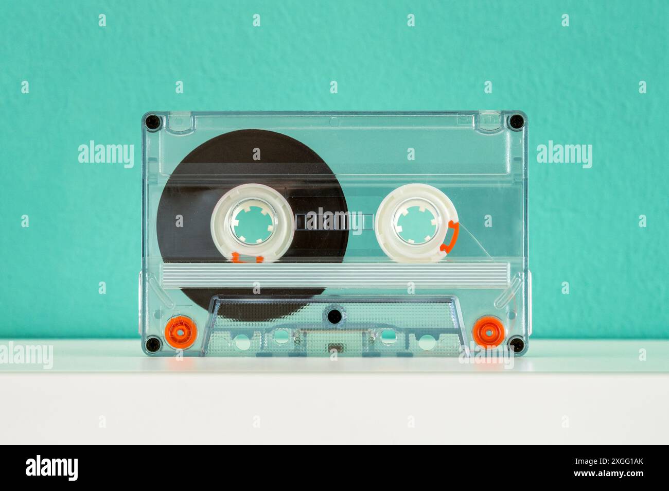 La cassetta audio trasparente si trova su uno scaffale bianco, evocando ricordi del passato e il suono iconico degli anni '80 e '90 Foto Stock