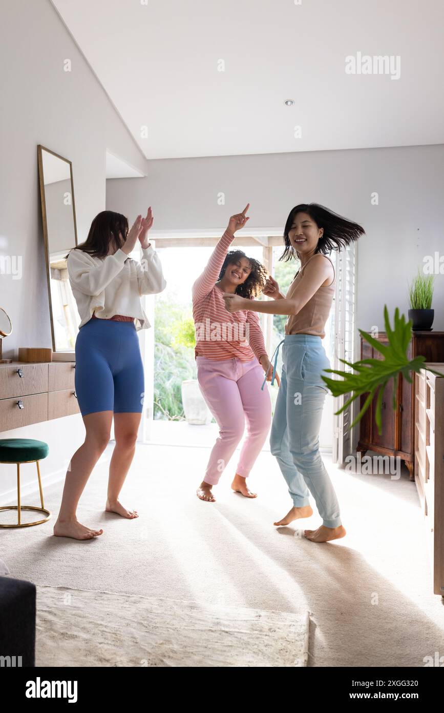 Ballando e divertendosi, tre amiche donne si divertono insieme a casa Foto Stock