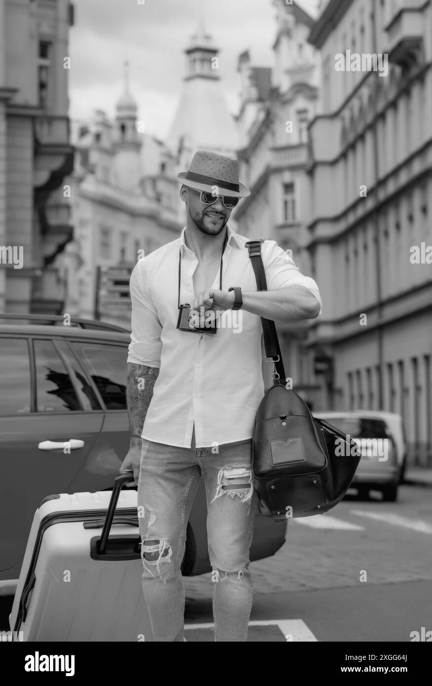 Ritratto di uomo di moda con bagagli, valigie in vacanza. Stile di vita di viaggio. Turista uomo d'affari che viaggia in città europea. Ricco sicuro Foto Stock