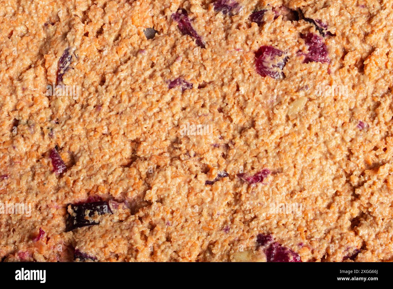 Primo piano di un impasto grezzo con una consistenza granulare, ruvida e un colore dorato-marrone. All'interno della superficie sono presenti frammenti scuri che aggiungono una raffica di col Foto Stock