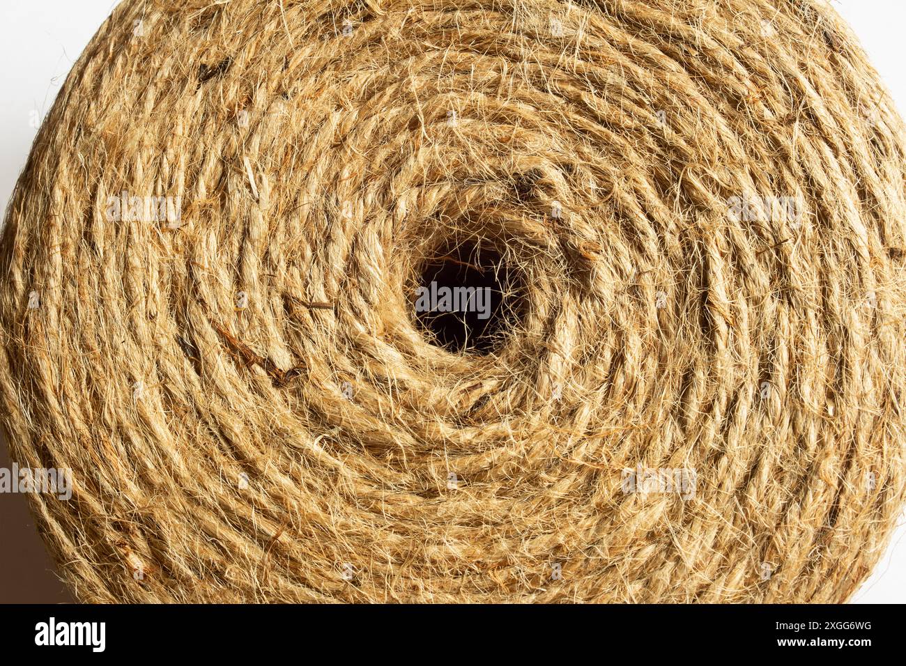 Immagine ravvicinata di un rotolo di spago di iuta naturale visto dall'alto che mostra il foro centrale, mostrando la sua trama intricata e fibrosa cattura il de Foto Stock