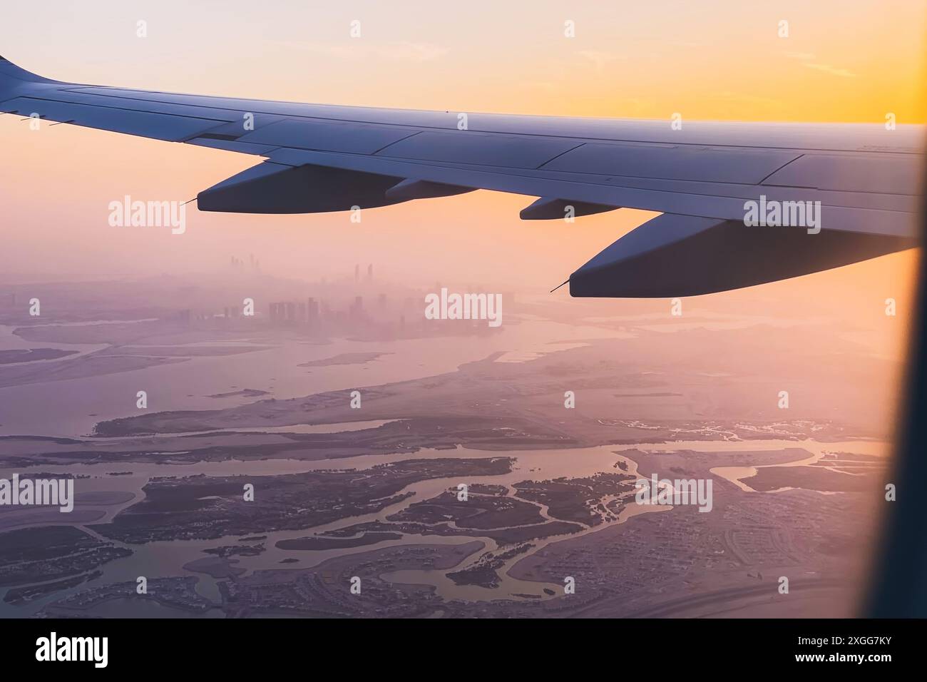 Dal punto di vista dei passeggeri, vista dalla finestra panoramica dello skyline di Abu Dhabi e della città con fiumi e paesaggi deserti al tramonto. Voli con compagnie aeree low budget holi Foto Stock