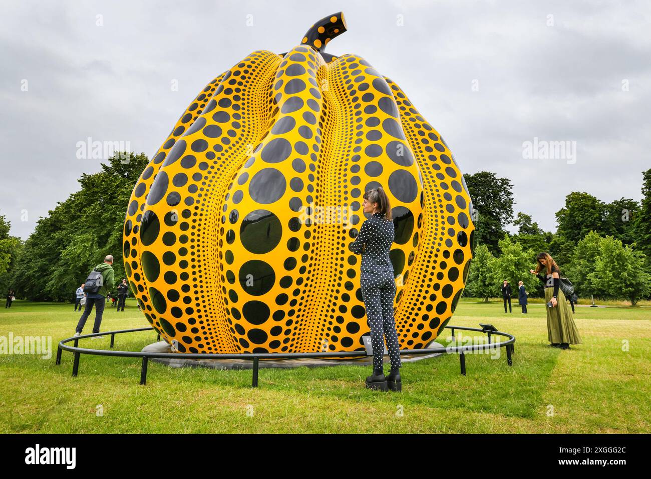 Londra, Regno Unito. 9 luglio 2024. Il visitatore Esther guarda la scultura, vestita con un abito coordinato con molti punti. Questa grande scultura, 'zucca' (2024), realizzata dal giapponese Yayoi Kusama, sarà in situ presso lo stagno rotondo nei giardini di Kensington fino a novembre ed è visitabile liberamente nei giardini. È la più grande scultura di zucca in bronzo di Kusama fino ad oggi. Crediti: Imageplotter/Alamy Live News Foto Stock